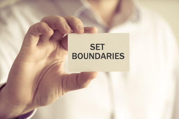 Businessman holding SET BOUNDARIES message card